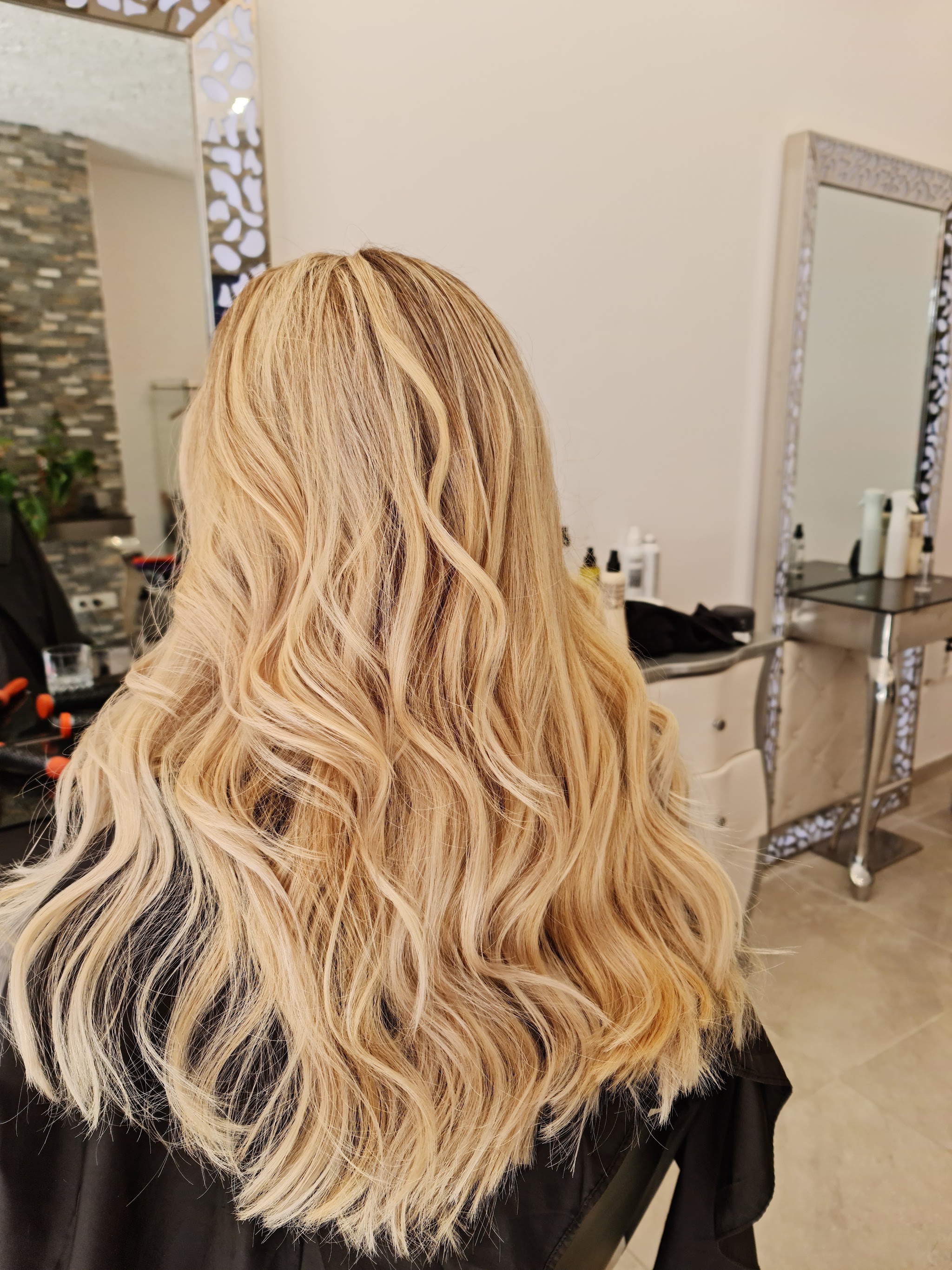 Goudblond lang haar met golven, voor een spiegel in de salon