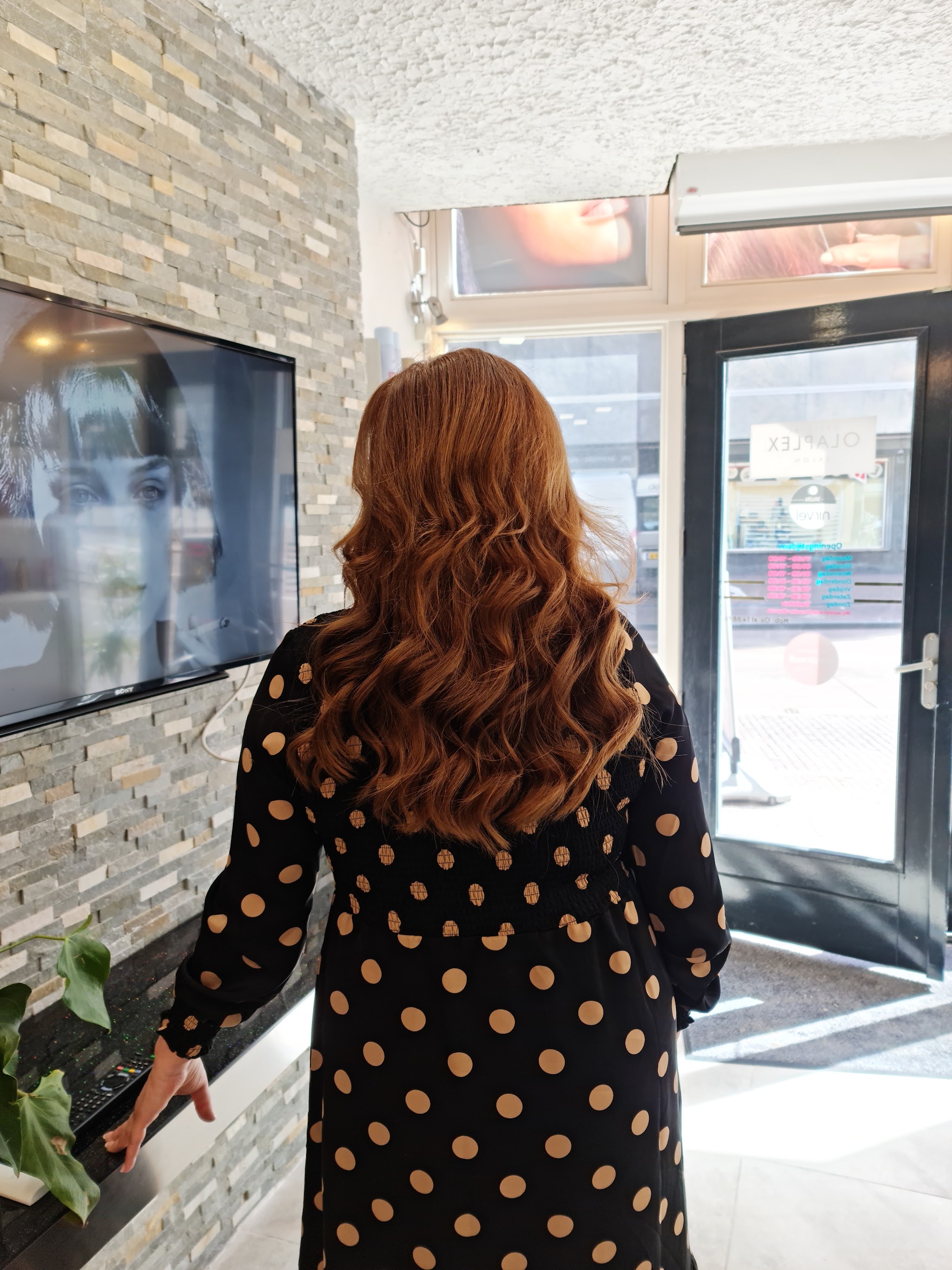 Klant met koperkleurige golven bij de ingang van de salon